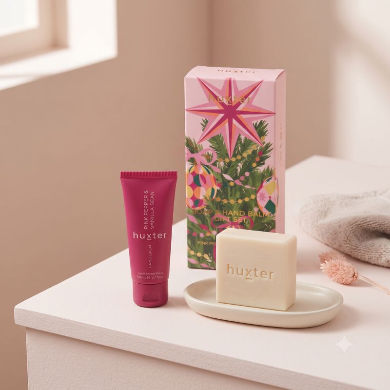 Huxter Pink Pepper and Vanilla Bean gift set displayed on a vanity with hand balm and cream soap bar