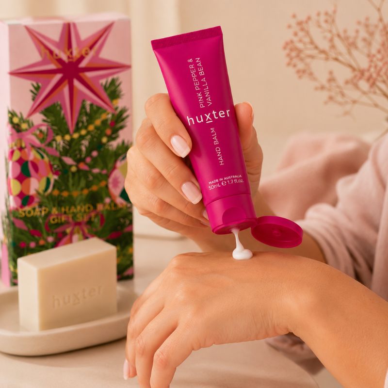 Close-up of Huxter Pink Pepper and Vanilla Bean Hand Balm being dispensed onto a woman’s hand