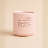 Pink speckled ceramic planter with “You are all kinds of amazing” quote on beige background