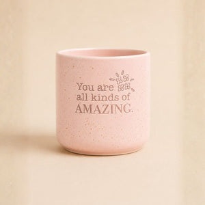 Pink speckled ceramic planter with “You are all kinds of amazing” quote on beige background
