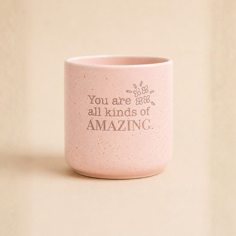 Pink speckled ceramic planter with “You are all kinds of amazing” quote on beige background