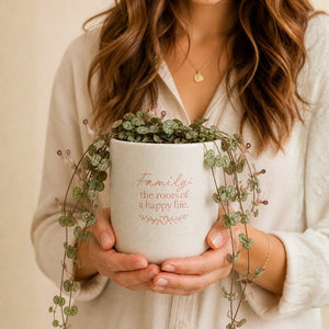 Woman holding Splosh family quote ceramic planter with trailing vine plant