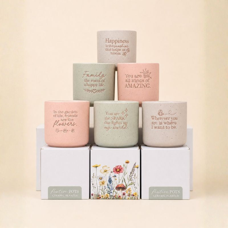 Collection of inspirational ceramic planters in pink, sage, and neutral tones stacked display