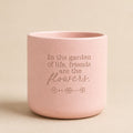 Pink ceramic quote planter with “In the garden of life, friends are the flowers” on beige background