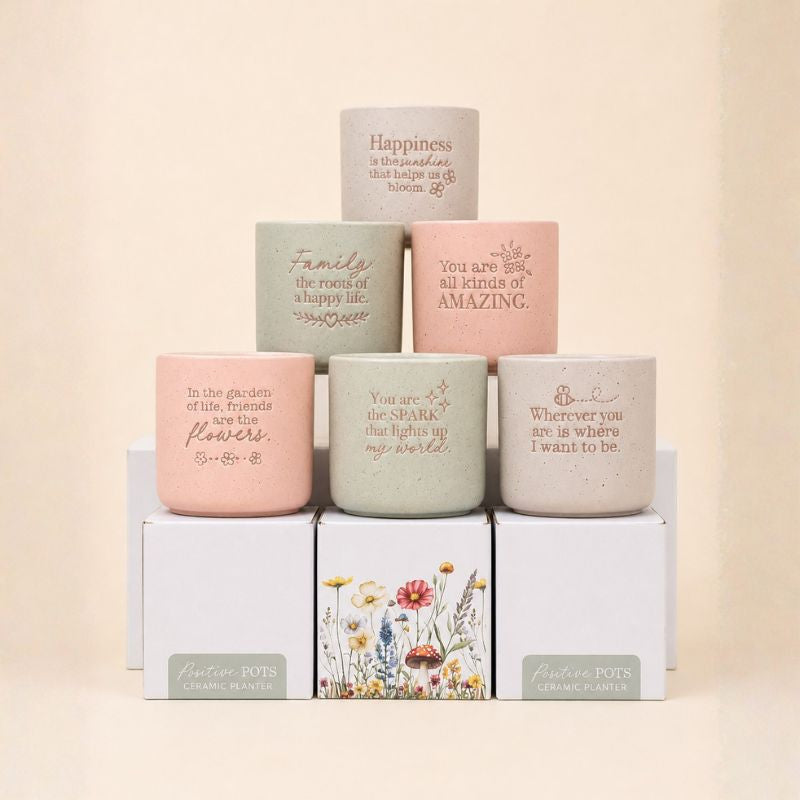 Collection of pastel ceramic quote planters arranged in neutral setting