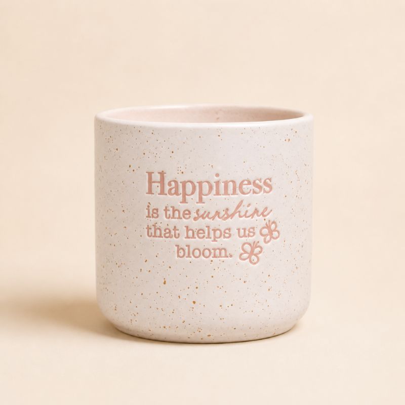 Neutral ceramic quote planter with “Happiness is the sunshine that helps us bloom” on beige background