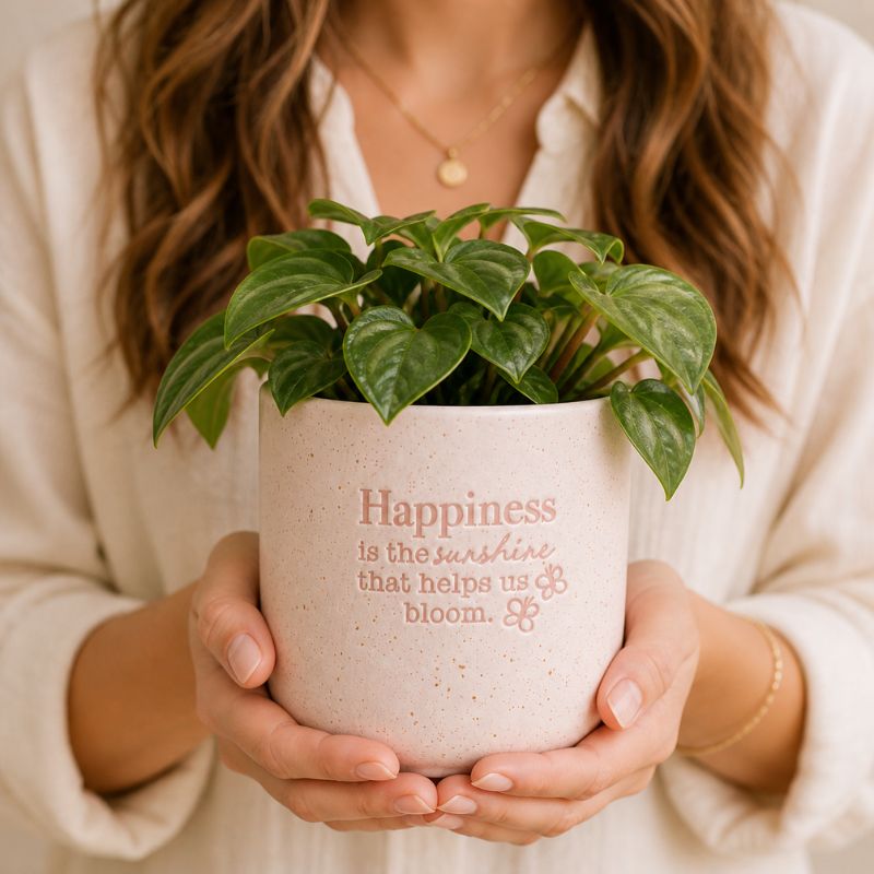 Woman holding ceramic happiness quote planter with green houseplant