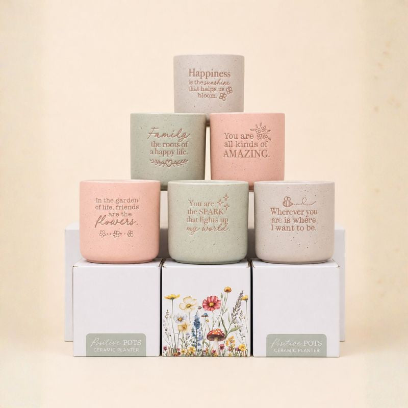 Collection of pastel ceramic quote planters arranged in soft neutral setting