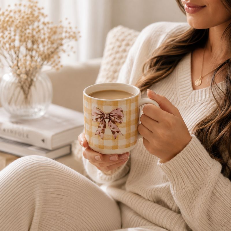A woman in a cozy cream-colored knit sweater holds a Splosh -Saddle & Bloom Bow Mug