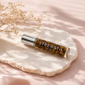 Roll-on bottle labeled 'STRENGTH' on a stone surface with dried flowers.