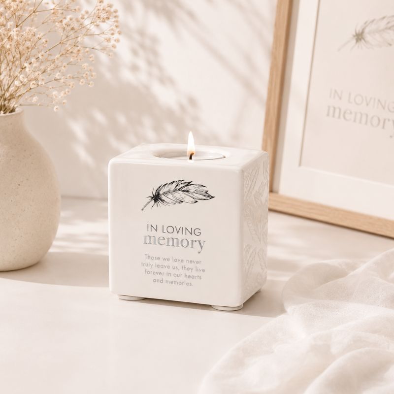 Candle in a white container with 'In Loving Memory' text on a soft background