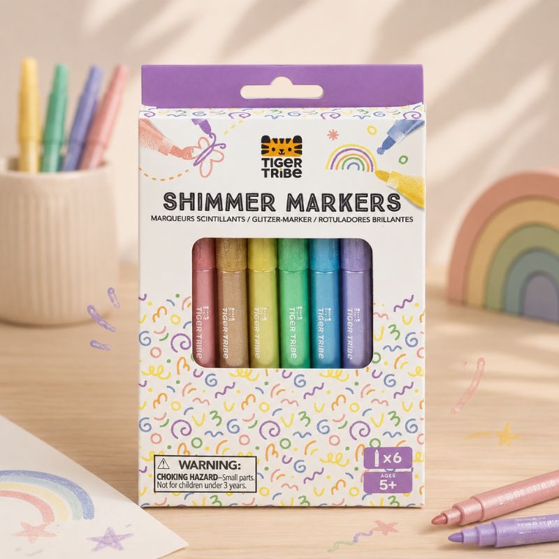 Packaging of Tiger Tribe Shimmer Markers on a wooden surface with markers and rainbow decorations. - Loveshack Giftware