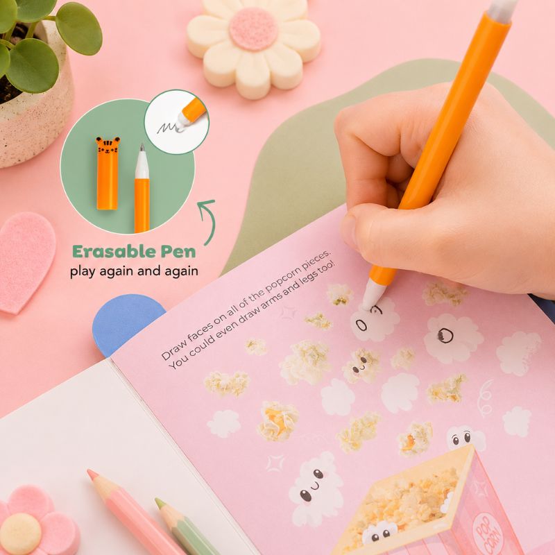 Erasable pen being used on a pink notebook with cartoon popcorn designs, surrounded by stationery items.