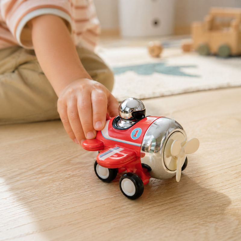 Child playing with Tiger Tribe Presto Plane push toy on wooden surface