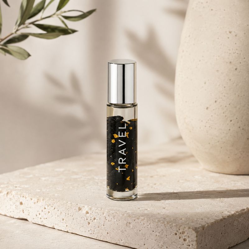 Roll-on bottle labeled 'TRAVEL' on a textured surface with a plant in the background