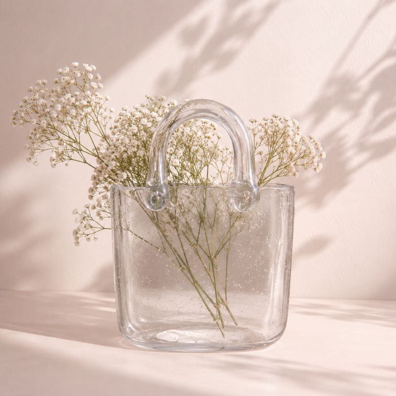 Clear glass bag with baby's breath flowers on a soft pink background